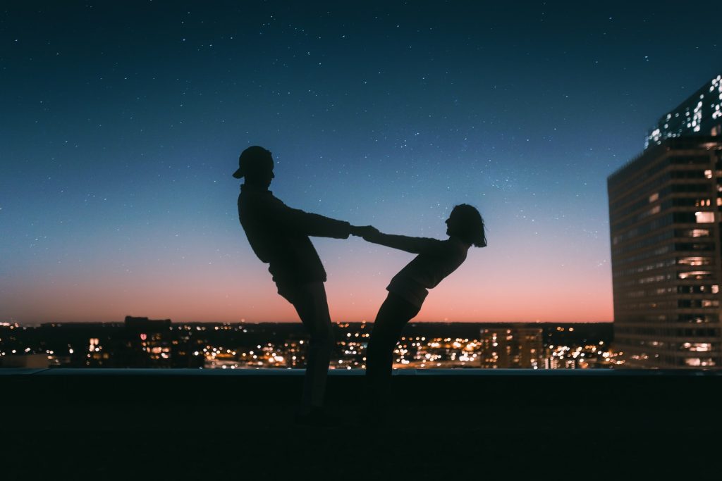 En kille och tjej håller händerna med en stad som bakgrund